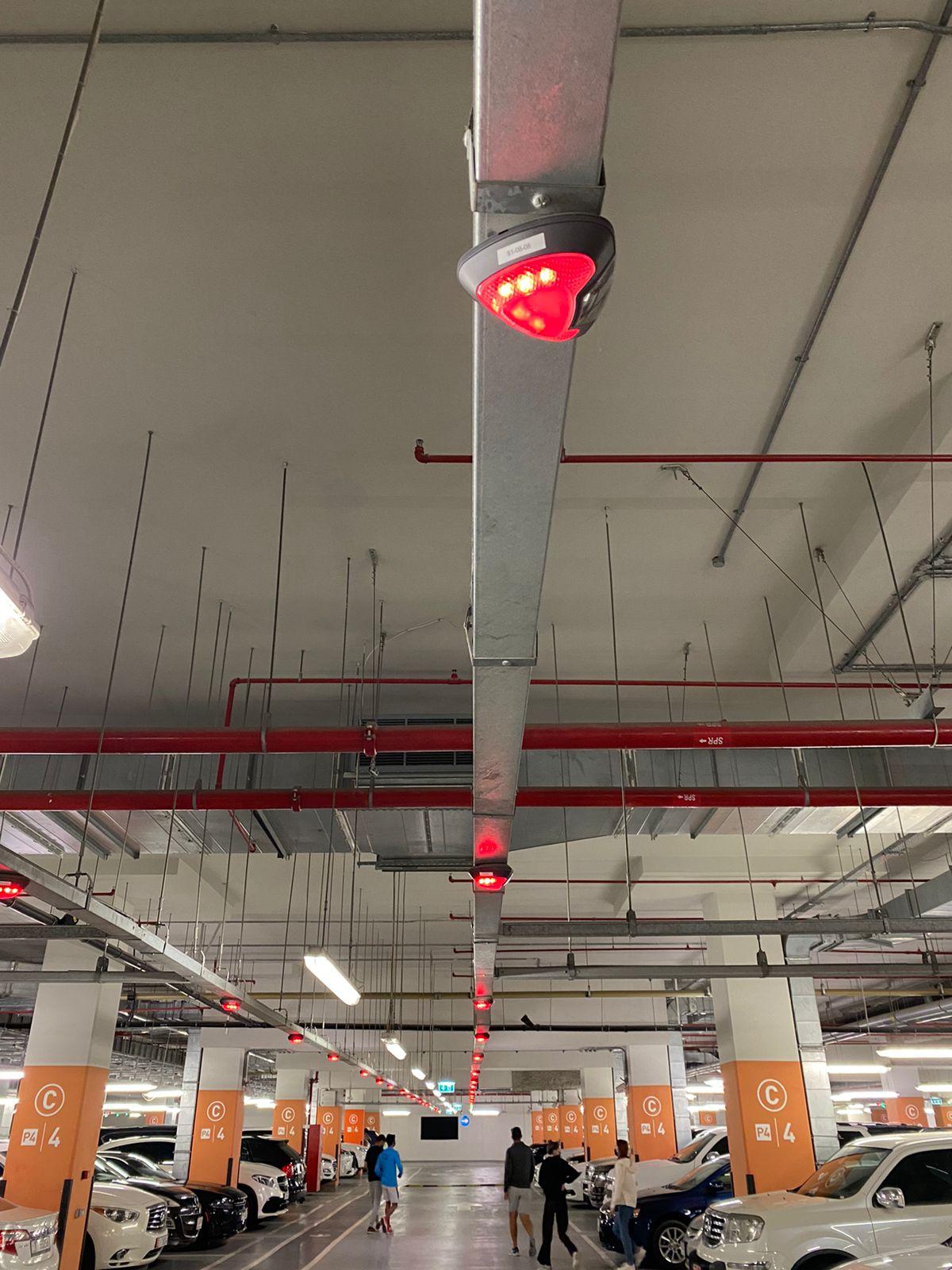 Parking guidance system - Close-up of ultrasonic bay sensors mounted on ceiling bracket showing red indicators
