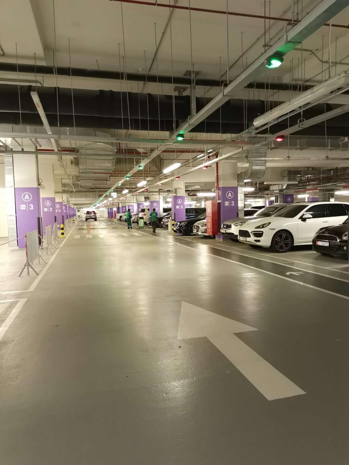 Parking guidance system - wide aisle shot of a UAE carpark showing green and red bay indicators clearly visible from a distance